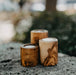 Three wooden candle holders on a stone surface with a blurred natural background