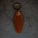 Brown leather keychain with gold ring on a gray background