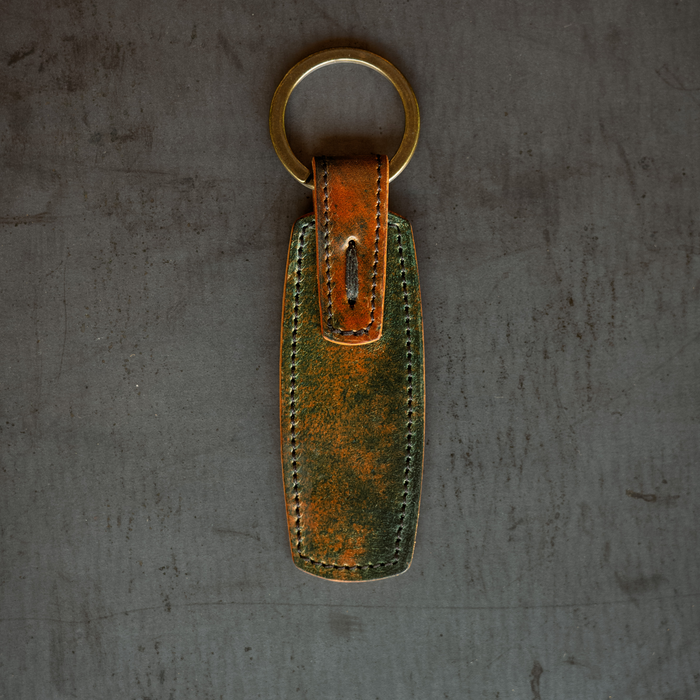Leather key fob with a gold ring on a textured gray background