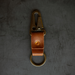 Brown leather key fob with brass clip on a dark gray background