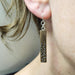 Wooden bar earring with silver beads worn by a person