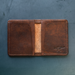 Brown leather wallet with visible brand logo on a textured blue background